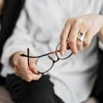 Close-up of a woman holding glasses, symbolizing thought and professionalism.