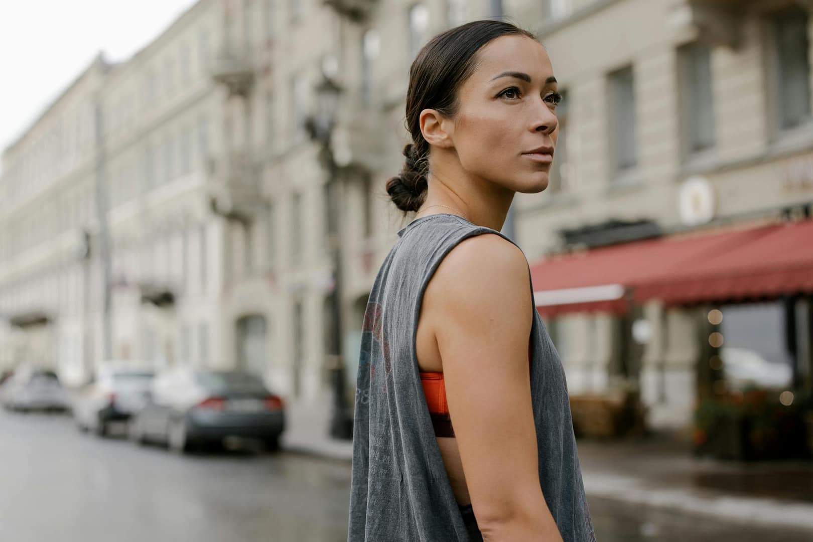 A woman in a sleeveless top confidently walking through a stylish city street, showcasing modern urban fashion.